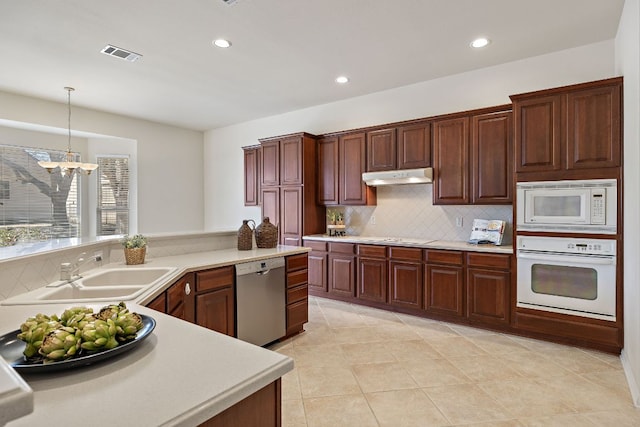 kitchen featuring white appliances, visible vents, light countertops, under cabinet range hood, and a sink