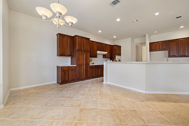 kitchen with recessed lighting, under cabinet range hood, visible vents, light countertops, and an inviting chandelier