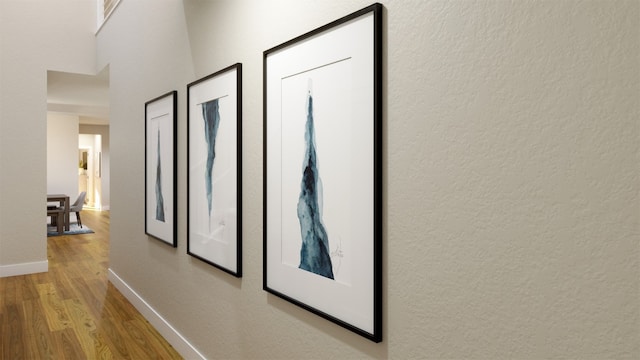 hall with baseboards, wood finished floors, and a textured wall