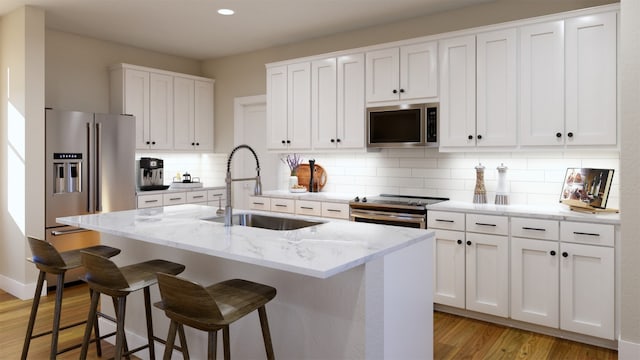 kitchen with light wood finished floors, backsplash, appliances with stainless steel finishes, white cabinets, and a sink