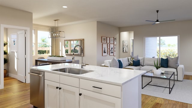 kitchen with light wood-style floors, open floor plan, a kitchen island with sink, a sink, and dishwasher