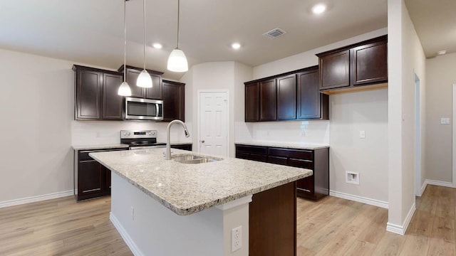 kitchen with decorative backsplash, appliances with stainless steel finishes, light wood-style floors, a sink, and dark brown cabinets