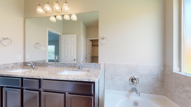 full bathroom featuring double vanity, a spacious closet, a sink, and a bath