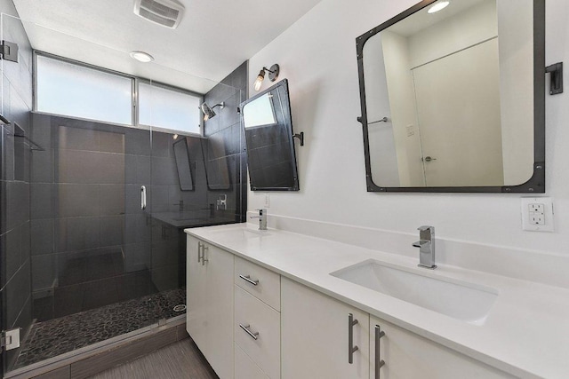 bathroom with a sink, visible vents, double vanity, and a shower stall