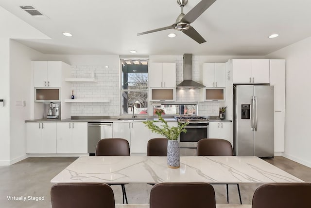 kitchen with backsplash, wall chimney exhaust hood, appliances with stainless steel finishes, and a sink