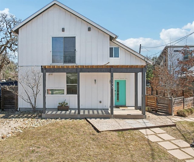 back of property featuring covered porch, board and batten siding, and fence