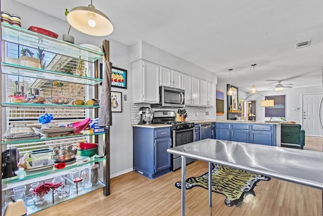 kitchen featuring stainless steel appliances, a peninsula, visible vents, light wood finished floors, and tasteful backsplash