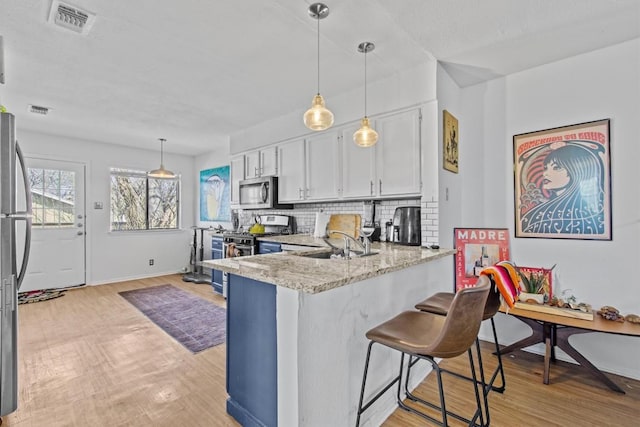 kitchen with tasteful backsplash, appliances with stainless steel finishes, white cabinets, a peninsula, and a kitchen breakfast bar