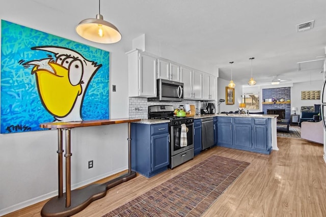 kitchen featuring light wood finished floors, visible vents, appliances with stainless steel finishes, blue cabinets, and a peninsula