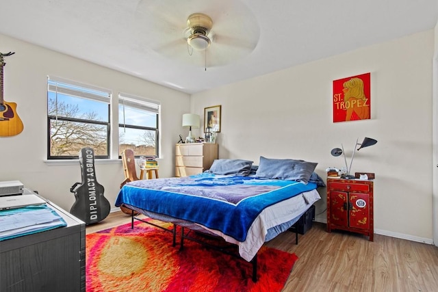 bedroom with ceiling fan, wood finished floors, and baseboards