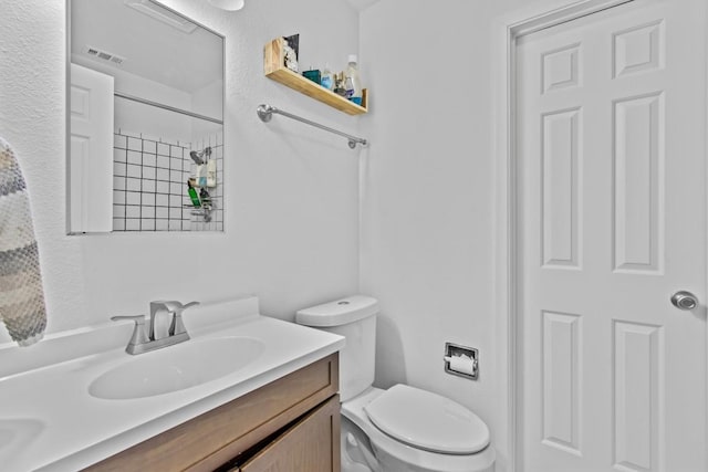 bathroom featuring toilet, walk in shower, vanity, and visible vents