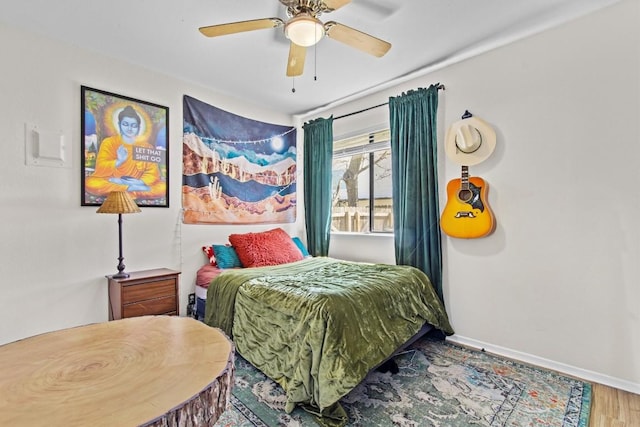 bedroom featuring a ceiling fan, baseboards, and wood finished floors