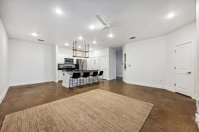 kitchen with finished concrete flooring, stainless steel appliances, an island with sink, and recessed lighting