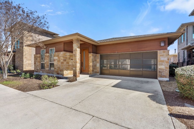 view of front of home featuring an attached garage, stone siding, and concrete driveway