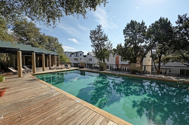 pool featuring a deck, fence, and a residential view