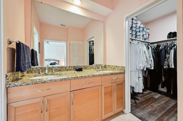 ensuite bathroom featuring double vanity, ensuite bath, visible vents, and a sink