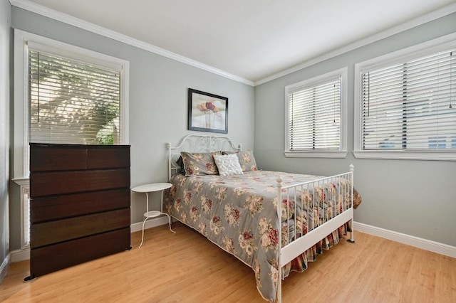 bedroom with crown molding, baseboards, and wood finished floors