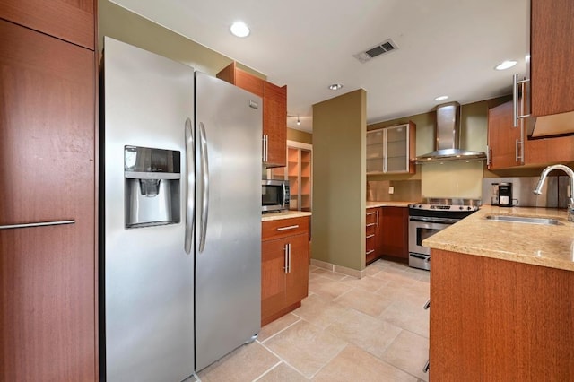 kitchen with visible vents, brown cabinetry, wall chimney exhaust hood, stainless steel appliances, and a sink