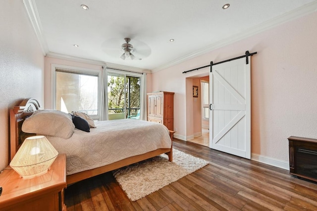 bedroom with ornamental molding, a barn door, wood finished floors, and baseboards