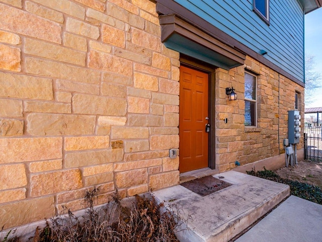 entrance to property with stone siding and fence