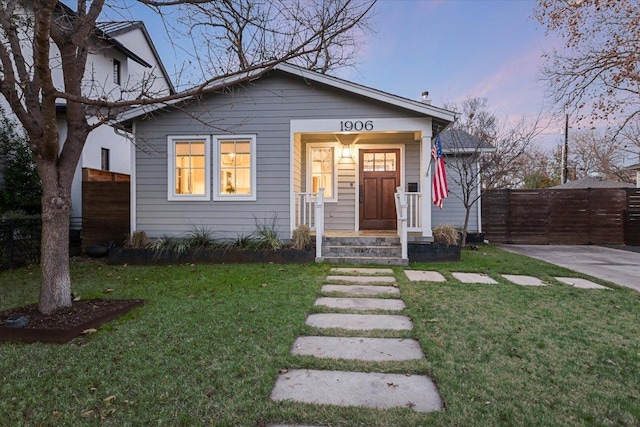 bungalow-style house with fence and a lawn