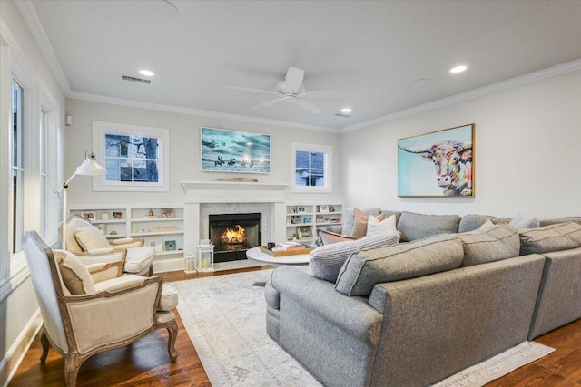 living room with dark wood-style flooring, crown molding, recessed lighting, visible vents, and a high end fireplace