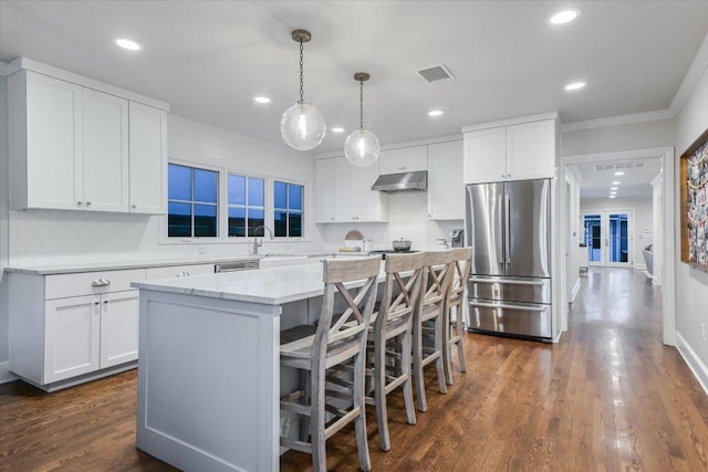 kitchen with visible vents, a kitchen island, dark wood-style flooring, freestanding refrigerator, and under cabinet range hood