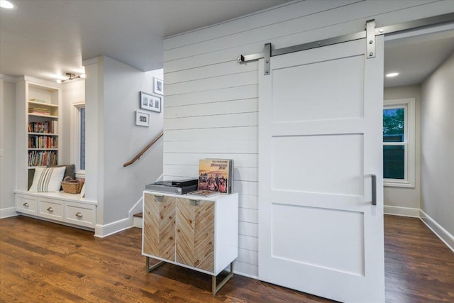 interior details with a barn door, wood finished floors, and baseboards