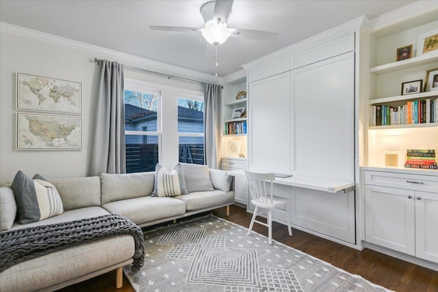 living area featuring built in features, a ceiling fan, built in study area, ornamental molding, and dark wood-type flooring