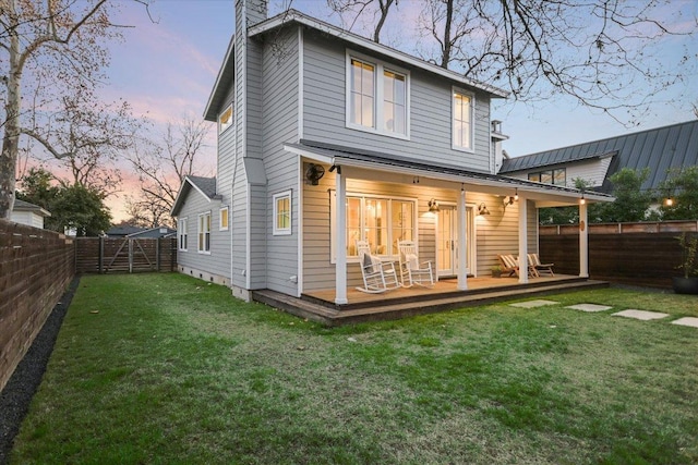 rear view of house with a fenced backyard, a chimney, a yard, a gate, and a wooden deck