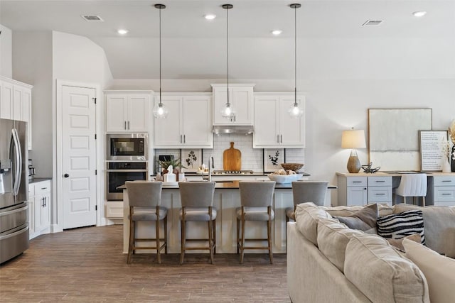 kitchen featuring appliances with stainless steel finishes, open floor plan, visible vents, and under cabinet range hood