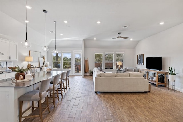 living area featuring vaulted ceiling, wood finished floors, a ceiling fan, and recessed lighting