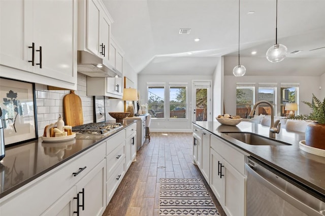 kitchen featuring visible vents, dark countertops, stainless steel appliances, under cabinet range hood, and a sink