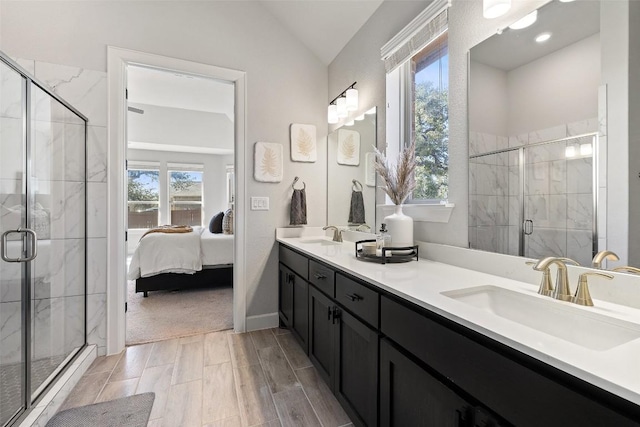 ensuite bathroom with double vanity, a stall shower, vaulted ceiling, a sink, and ensuite bath