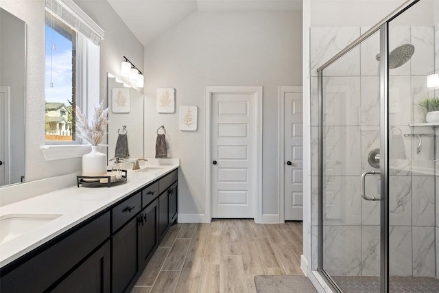 bathroom with vaulted ceiling, a sink, wood finished floors, and a shower stall