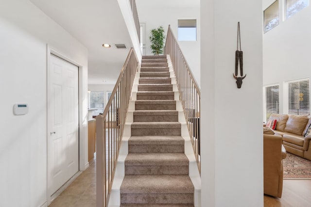 stairs featuring a high ceiling, visible vents, and recessed lighting