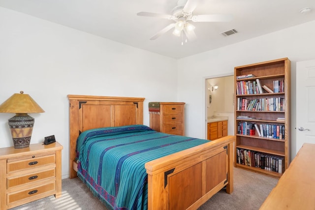 bedroom with ceiling fan, ensuite bath, visible vents, and light colored carpet