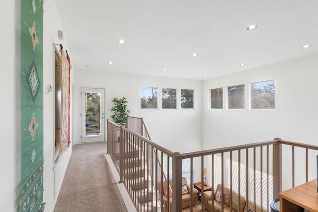 hall featuring light carpet, recessed lighting, and an upstairs landing