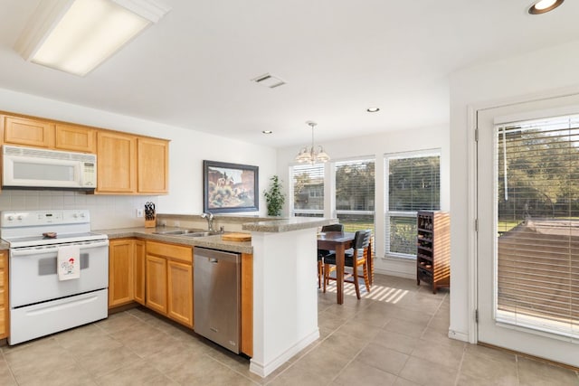 kitchen featuring white appliances, a healthy amount of sunlight, a sink, and a peninsula