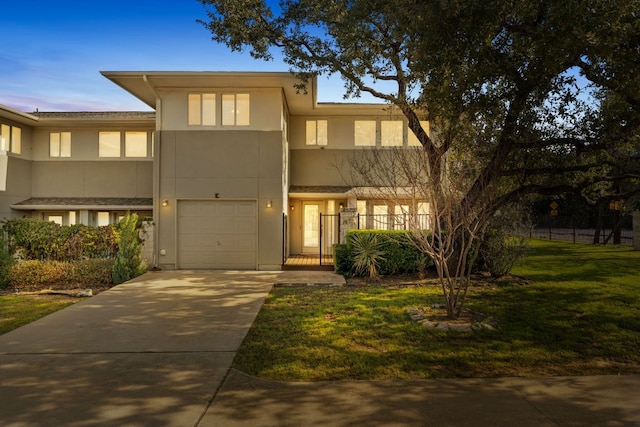 townhome / multi-family property with a garage, a front yard, driveway, and stucco siding