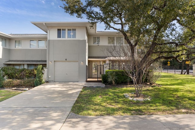 townhome / multi-family property with an attached garage, fence, driveway, stucco siding, and a front yard