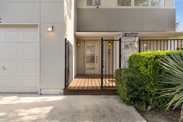 entrance to property with stone siding, an attached garage, visible vents, and stucco siding