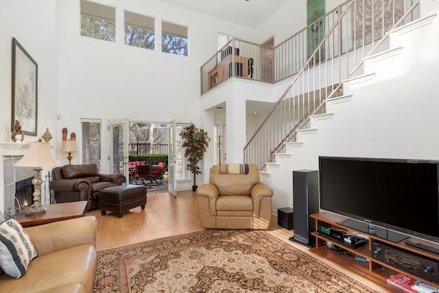 living room with a towering ceiling, stairway, and wood finished floors