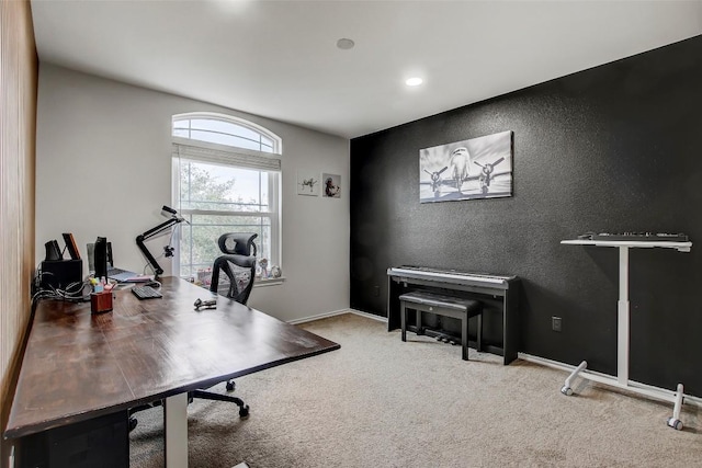 carpeted home office featuring a textured wall and baseboards