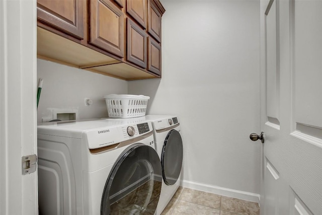 washroom featuring baseboards, light tile patterned floors, cabinet space, and washer and dryer