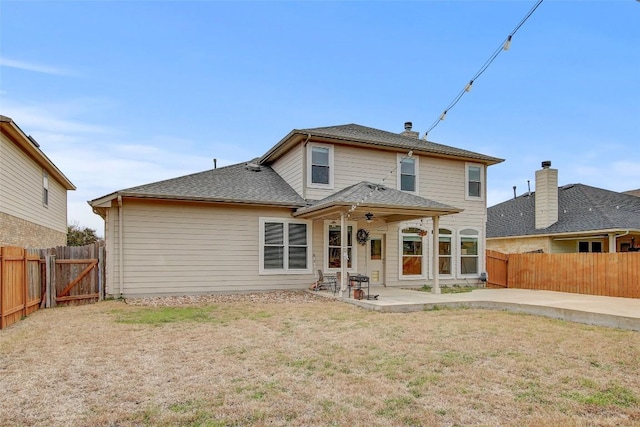 back of house with a patio area, a fenced backyard, a lawn, and roof with shingles