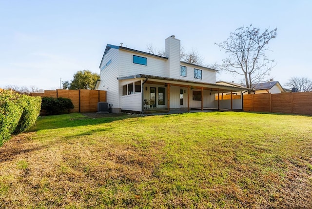 rear view of property featuring a yard, central AC unit, a chimney, and a fenced backyard