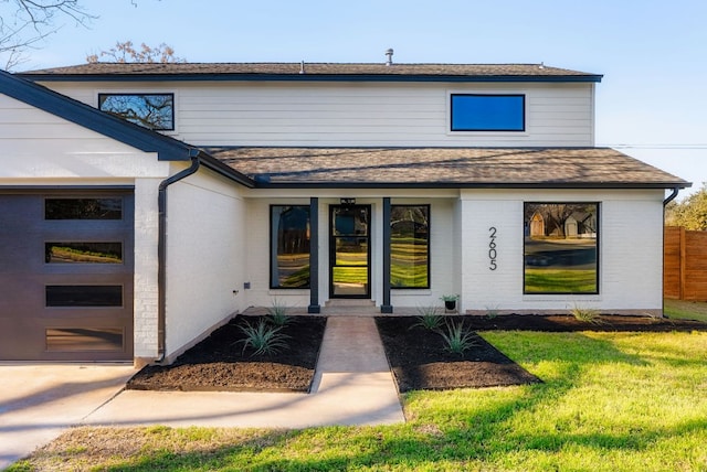 property entrance featuring brick siding, roof with shingles, an attached garage, and fence