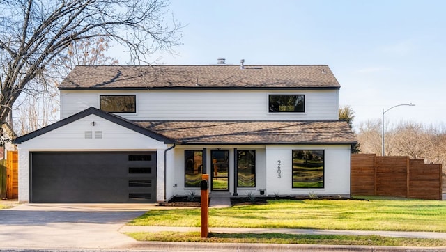 view of front of property featuring roof with shingles, concrete driveway, a front yard, fence, and a garage