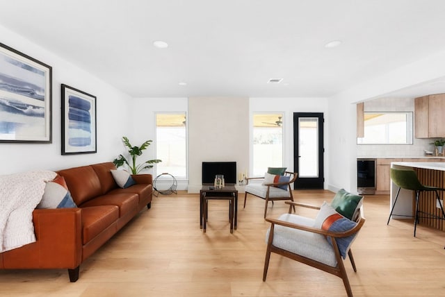 living area featuring light wood-type flooring, beverage cooler, visible vents, and recessed lighting